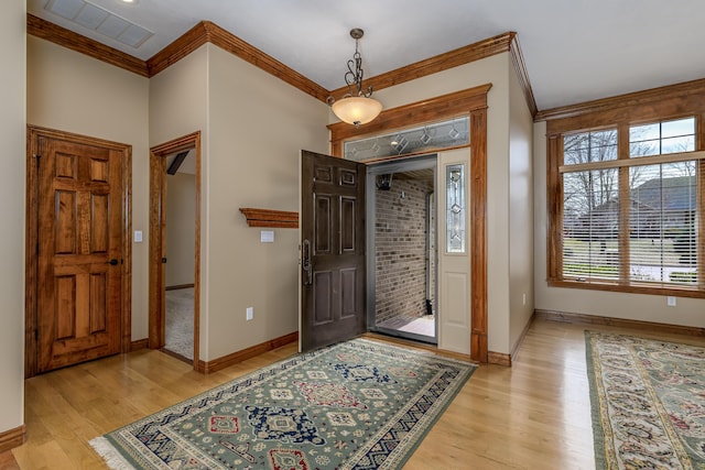 foyer featuring light wood-style flooring, visible vents, and crown molding