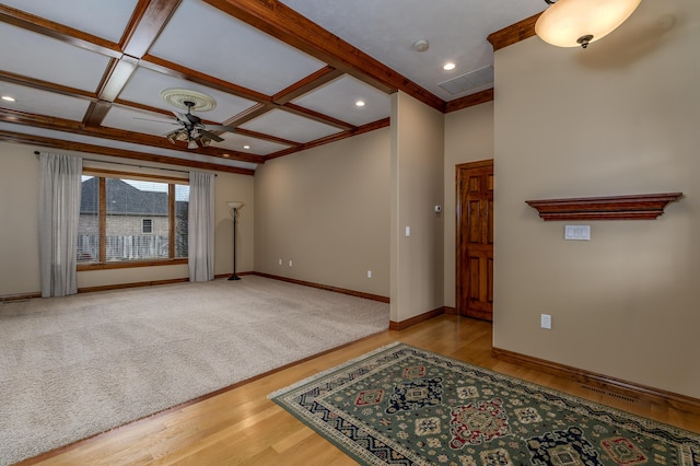 interior space with coffered ceiling, wood finished floors, a ceiling fan, baseboards, and crown molding