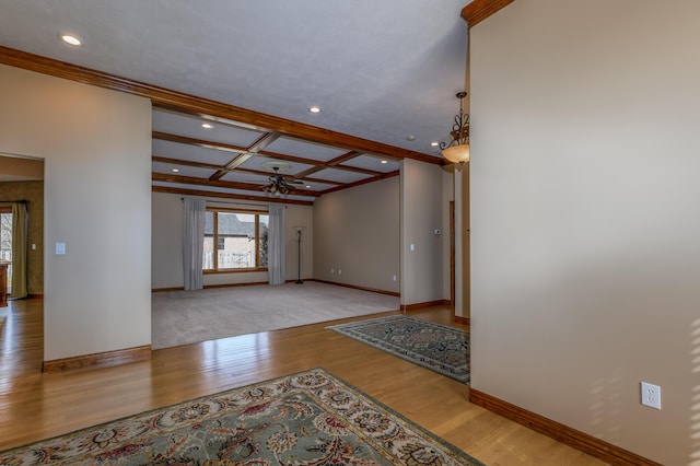 interior space featuring beam ceiling, light wood finished floors, ceiling fan, coffered ceiling, and baseboards