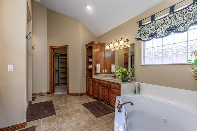 full bath featuring a walk in closet, lofted ceiling, vanity, a jetted tub, and baseboards