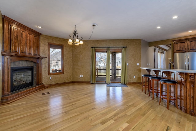 kitchen featuring a breakfast bar, stainless steel fridge, a fireplace, and light wood-style flooring