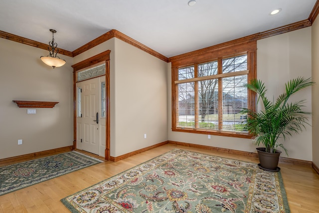 foyer featuring baseboards, ornamental molding, and wood finished floors