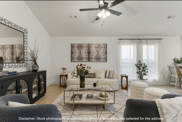 living area featuring a ceiling fan, visible vents, baseboards, and wood finished floors