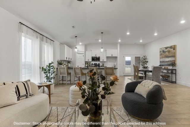 living room featuring light wood finished floors, plenty of natural light, baseboards, and recessed lighting