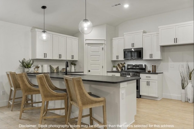 kitchen with dark countertops, visible vents, appliances with stainless steel finishes, white cabinets, and a peninsula