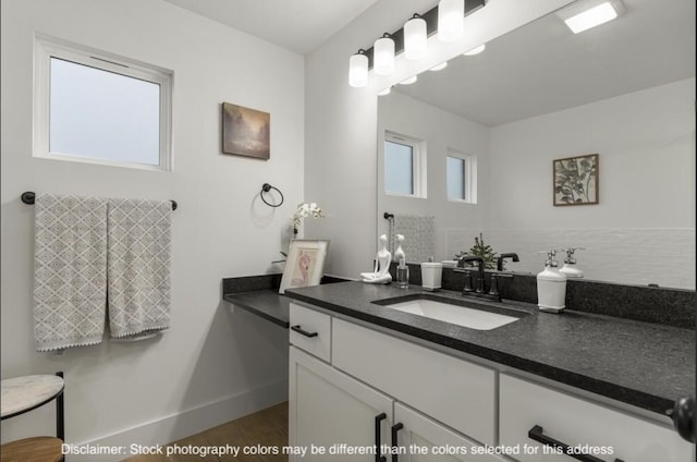 bathroom with baseboards, wood finished floors, vanity, and decorative backsplash