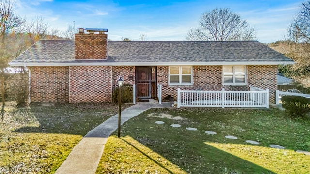 view of front of property featuring brick siding, fence, roof with shingles, a chimney, and a front yard