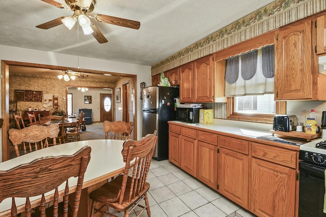 kitchen featuring light countertops, freestanding refrigerator, gas stove, a textured ceiling, and wallpapered walls