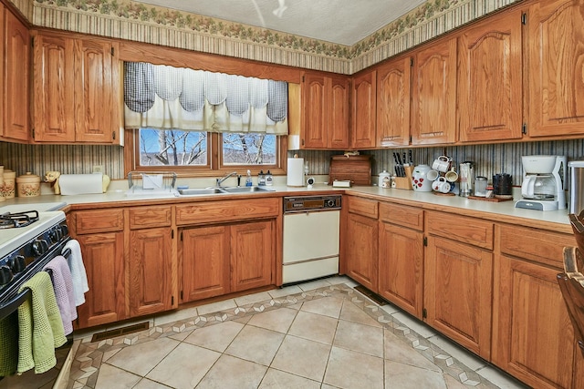 kitchen with brown cabinetry, gas stove, light countertops, and light tile patterned floors