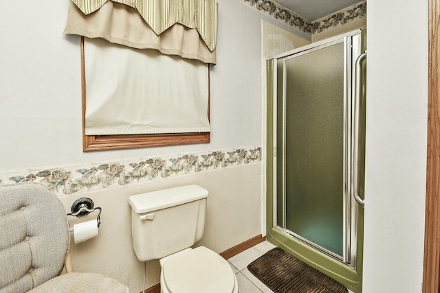 bathroom with a wainscoted wall, a stall shower, tile patterned flooring, and toilet