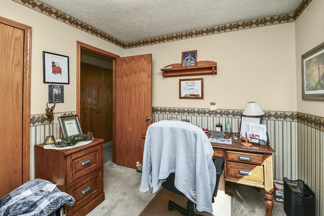 carpeted home office featuring a wainscoted wall and a textured ceiling