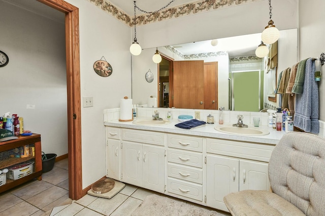 bathroom with baseboards, double vanity, a sink, and tile patterned floors