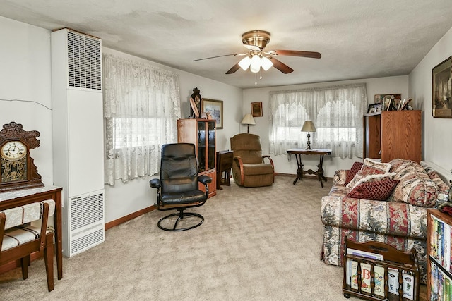 sitting room featuring carpet, a ceiling fan, a heating unit, a textured ceiling, and baseboards