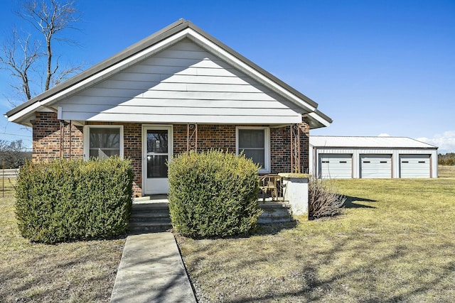 view of front of house with an outbuilding, a porch, a front yard, and brick siding