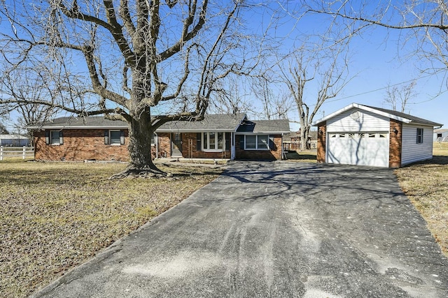 ranch-style home featuring an outbuilding, aphalt driveway, an attached garage, brick siding, and fence