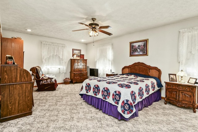 carpeted bedroom with a ceiling fan, baseboards, and a textured ceiling