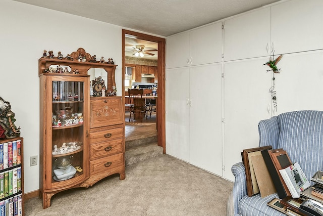 living area with a ceiling fan and light colored carpet