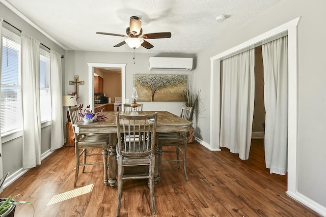 dining room featuring baseboards, a ceiling fan, wood finished floors, a textured ceiling, and an AC wall unit