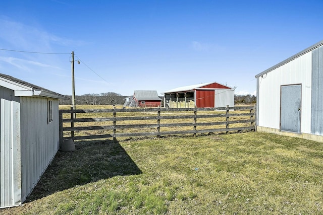 view of yard featuring an outbuilding, a pole building, a rural view, and fence