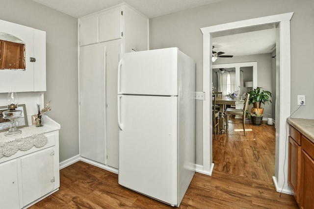 kitchen with dark wood-style floors, freestanding refrigerator, light countertops, and a ceiling fan