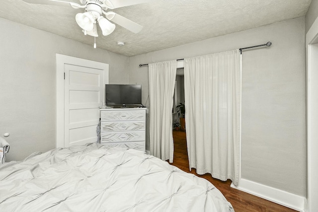 bedroom with a textured ceiling, wood finished floors, a ceiling fan, and baseboards