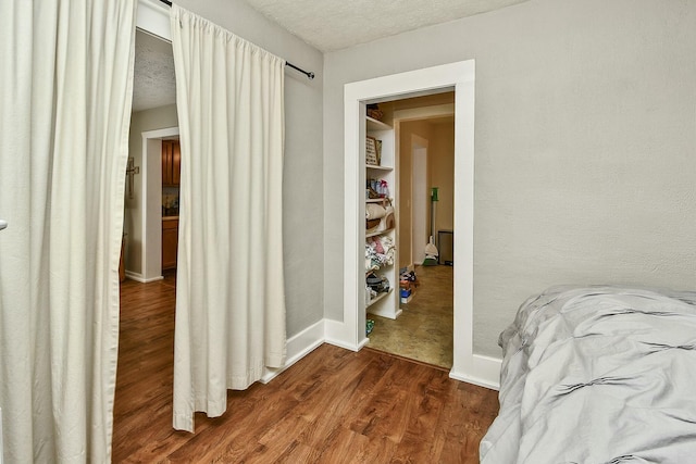 bedroom featuring dark wood-style flooring, a textured ceiling, and baseboards