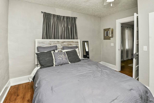 bedroom with a textured ceiling, ceiling fan, wood finished floors, and baseboards