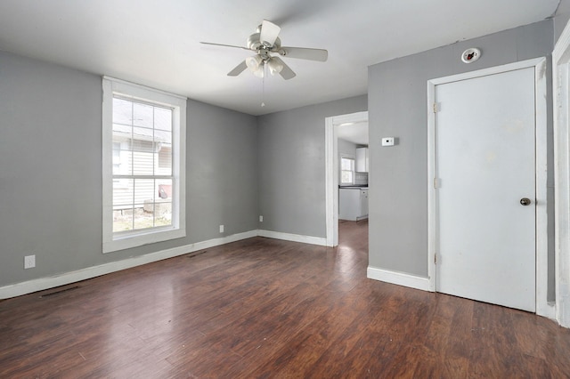 unfurnished room with a ceiling fan, visible vents, baseboards, and wood finished floors