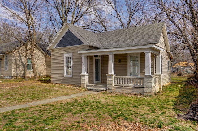 view of front facade with a shingled roof, a front lawn, and a porch