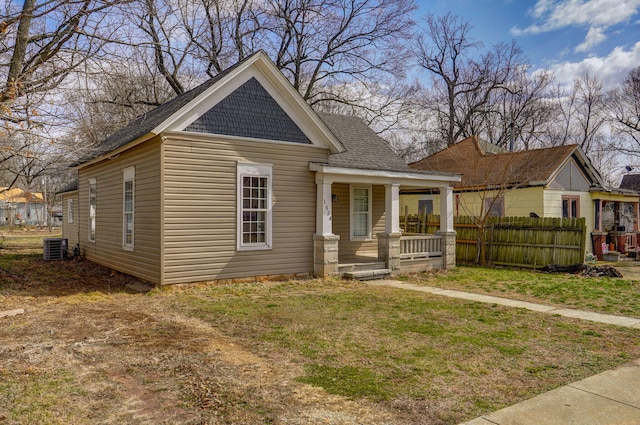 view of front of house with covered porch, central AC unit, a front yard, and fence