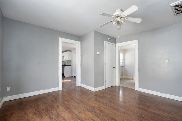 unfurnished room with baseboards, wood finished floors, visible vents, and a ceiling fan