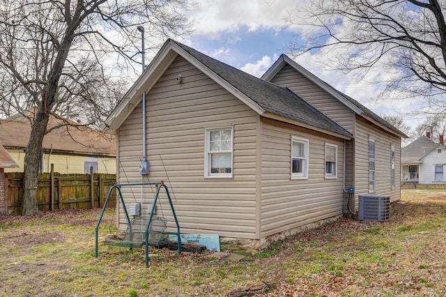 rear view of property with a shingled roof, cooling unit, and fence