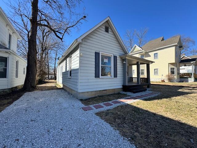 view of front of home with covered porch, driveway, and a front lawn