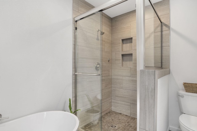 full bathroom with toilet, a stall shower, and a freestanding tub