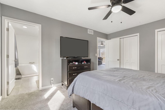 carpeted bedroom featuring connected bathroom, a ceiling fan, baseboards, visible vents, and multiple closets