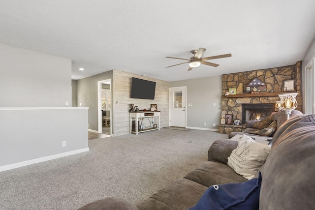 carpeted living area featuring a fireplace, a textured ceiling, baseboards, and ceiling fan