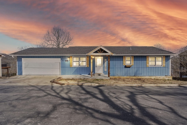 single story home with a shingled roof, driveway, and an attached garage