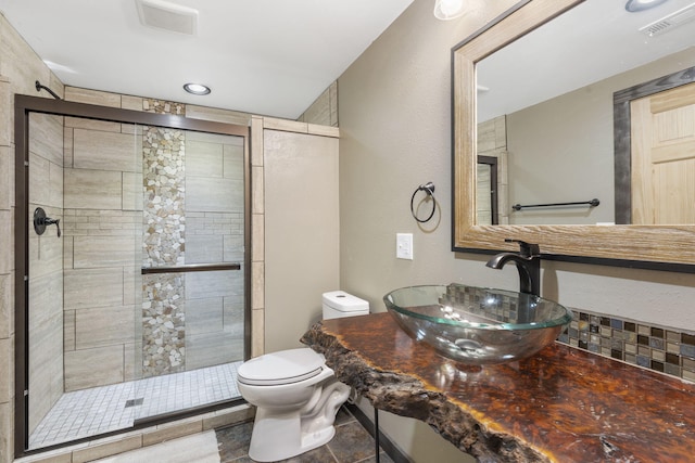 bathroom with visible vents, a stall shower, a sink, and toilet