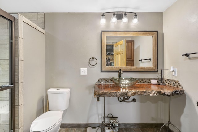 full bath featuring a sink, a tile shower, and toilet