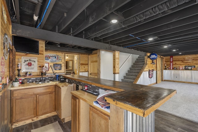 bar featuring wood walls, stairs, bar area, and wood finished floors