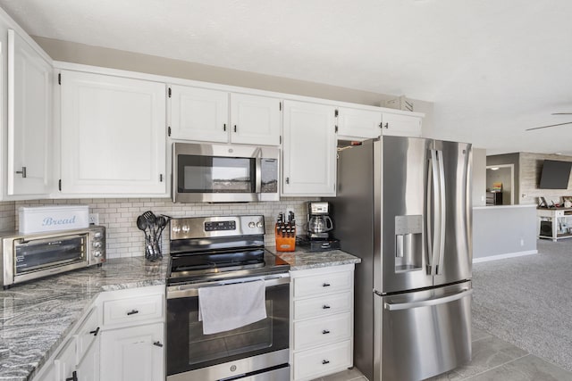 kitchen with light carpet, a toaster, decorative backsplash, stainless steel appliances, and white cabinetry