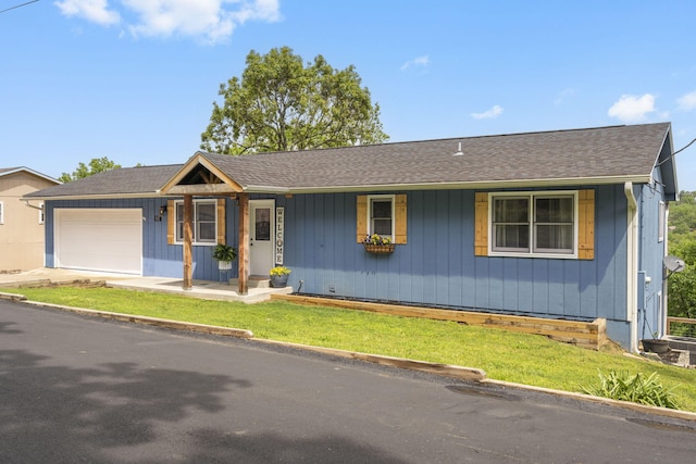 ranch-style home with a front yard, a shingled roof, board and batten siding, an attached garage, and driveway