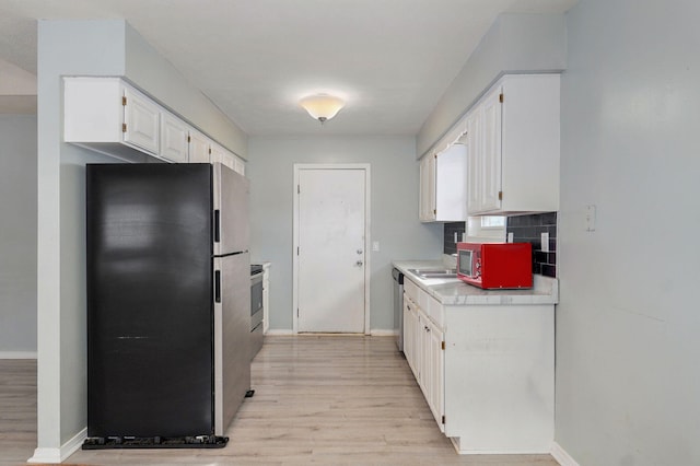 kitchen with stainless steel appliances, white cabinetry, light countertops, light wood-type flooring, and tasteful backsplash