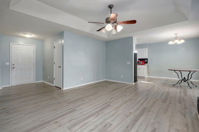 empty room with light wood-style floors, baseboards, and ceiling fan with notable chandelier