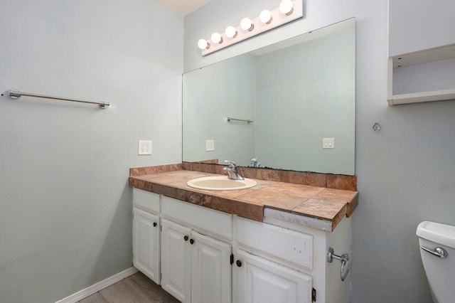 half bathroom featuring vanity, toilet, and baseboards