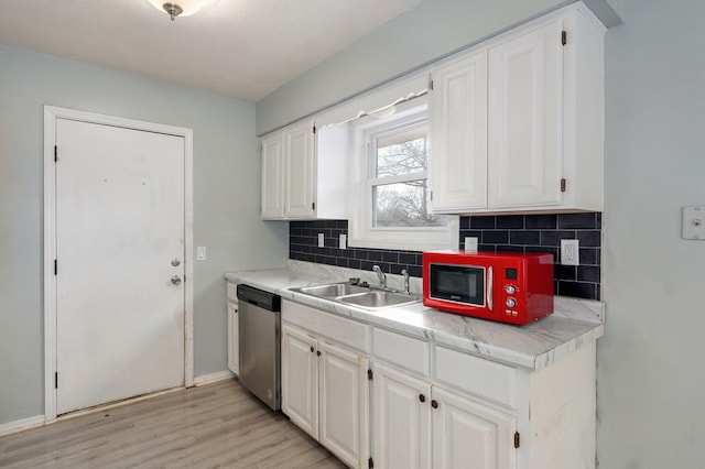 kitchen with light countertops, light wood-style flooring, backsplash, a sink, and dishwasher