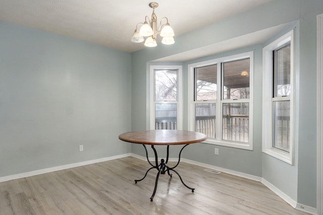 dining space with visible vents, baseboards, a chandelier, and wood finished floors