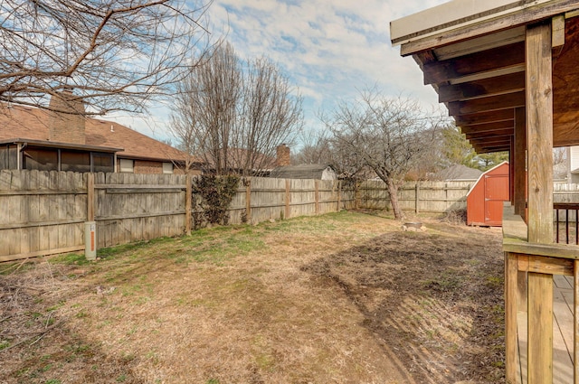 view of yard with an outbuilding, a fenced backyard, and a storage shed