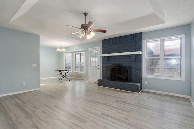 unfurnished living room with plenty of natural light, a raised ceiling, a fireplace, and wood finished floors