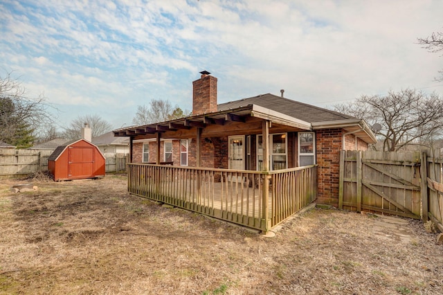 rear view of property featuring a chimney, an outbuilding, fence, a storage unit, and brick siding